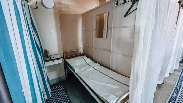 Yrjönkatu Swimming Hall cublicle with a bed, bedside table, hooks and privacy curtain