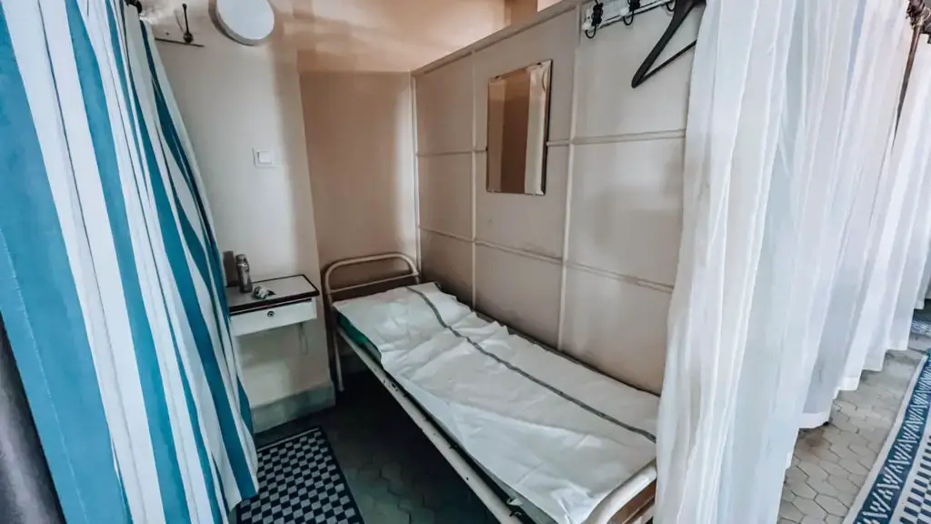 Yrjönkatu Swimming Hall cublicle with a bed, bedside table, hooks and privacy curtain